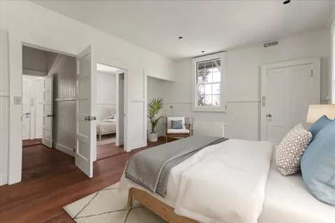 a spacious bedroom with a bed and wooden floor