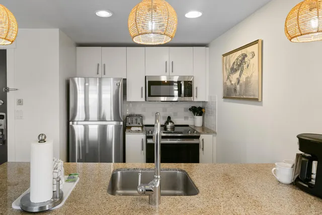 a kitchen with stainless steel appliances granite countertop a refrigerator and a stove top oven