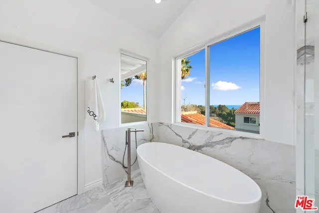 a bathroom with a white tub shower vanity and a mirror
