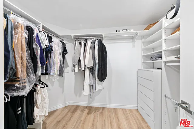 a view of walk in closet with clothes and shoes