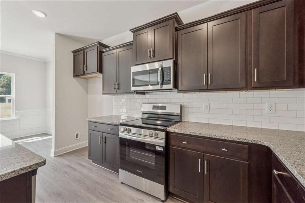 263 Eason Street Bowdon, GA 30108 - Photo 2 of 11 a kitchen with granite countertop wooden cabinets and stainless steel appliances