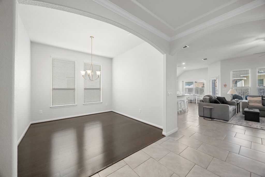 606 Linares Lane Austin, TX 78748 - Photo 19 of 35 Dining area with arched walkways, light tile patterned floors, crown molding, and a chandelier