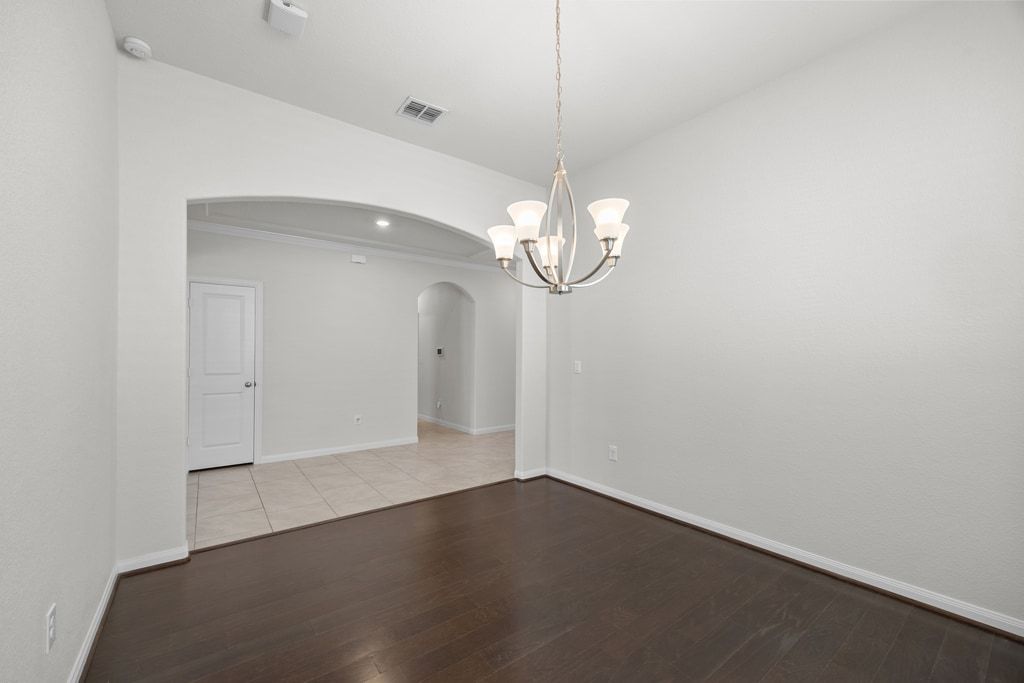 606 Linares Lane Austin, TX 78748 - Photo 20 of 35 Spare room featuring wood finished floors, arched walkways, and a chandelier