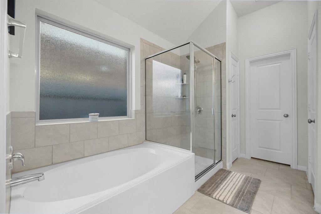 606 Linares Lane Austin, TX 78748 - Photo 22 of 35 Full bath featuring a bath, a shower stall, and light tile patterned flooring
