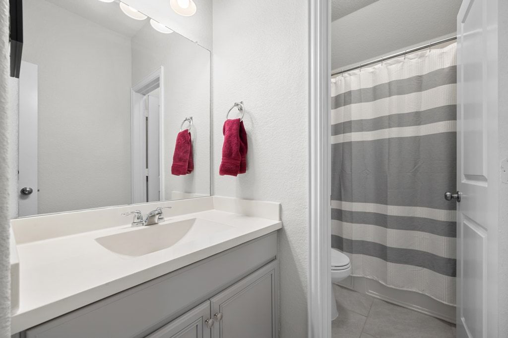 606 Linares Lane Austin, TX 78748 - Photo 25 of 35 Full bath featuring vanity, light tile patterned flooring, and a textured wall