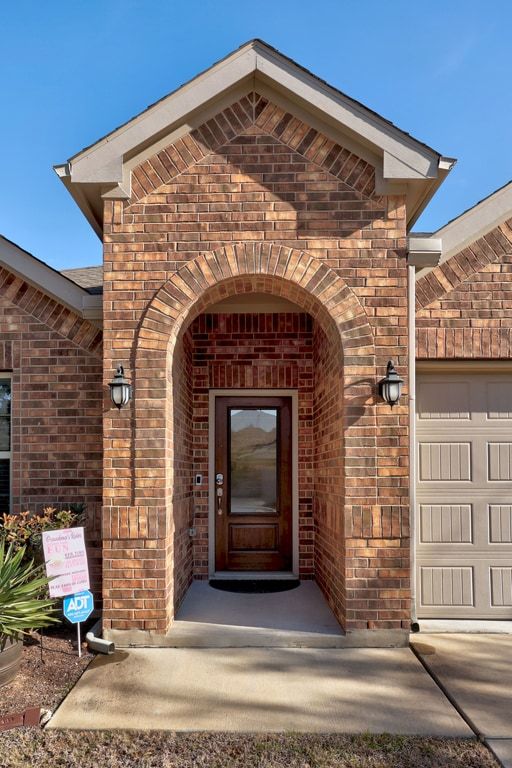 606 Linares Lane Austin, TX 78748 - Photo 32 of 35 View of exterior entry featuring brick siding and an attached garage
