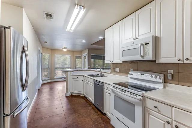 a kitchen with kitchen island a sink stainless steel appliances and cabinets