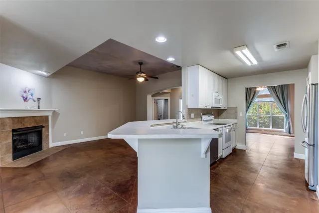 a view of an empty room with chandelier fan and fire place
