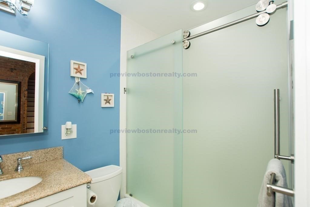 29 Brainerd Road, Unit 304 Boston, MA 02134 - Photo 20 of 22 a bathroom with a granite countertop shower sink vanity and mirror