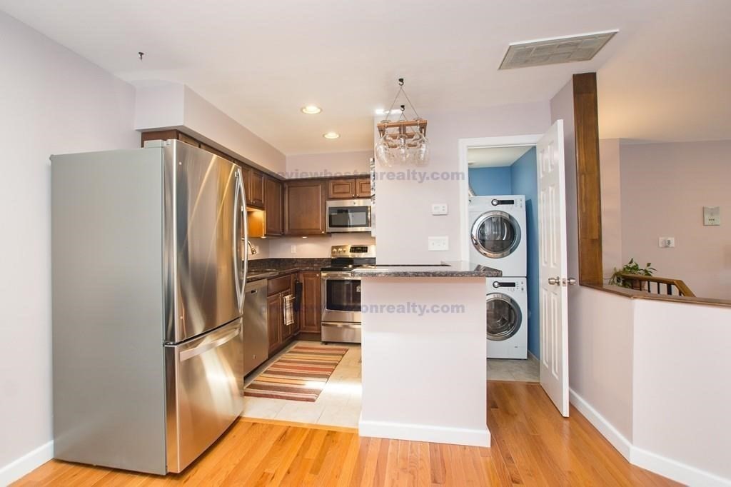 29 Brainerd Road, Unit 304 Boston, MA 02134 - Photo 2 of 22 a kitchen with kitchen island a counter top space a refrigerator and cabinets