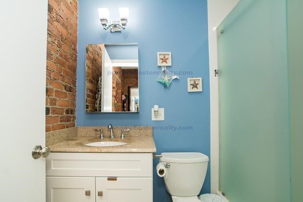29 Brainerd Road, Unit 304 Boston, MA 02134 - Photo 21 of 22 a bathroom with a granite countertop toilet sink and mirror