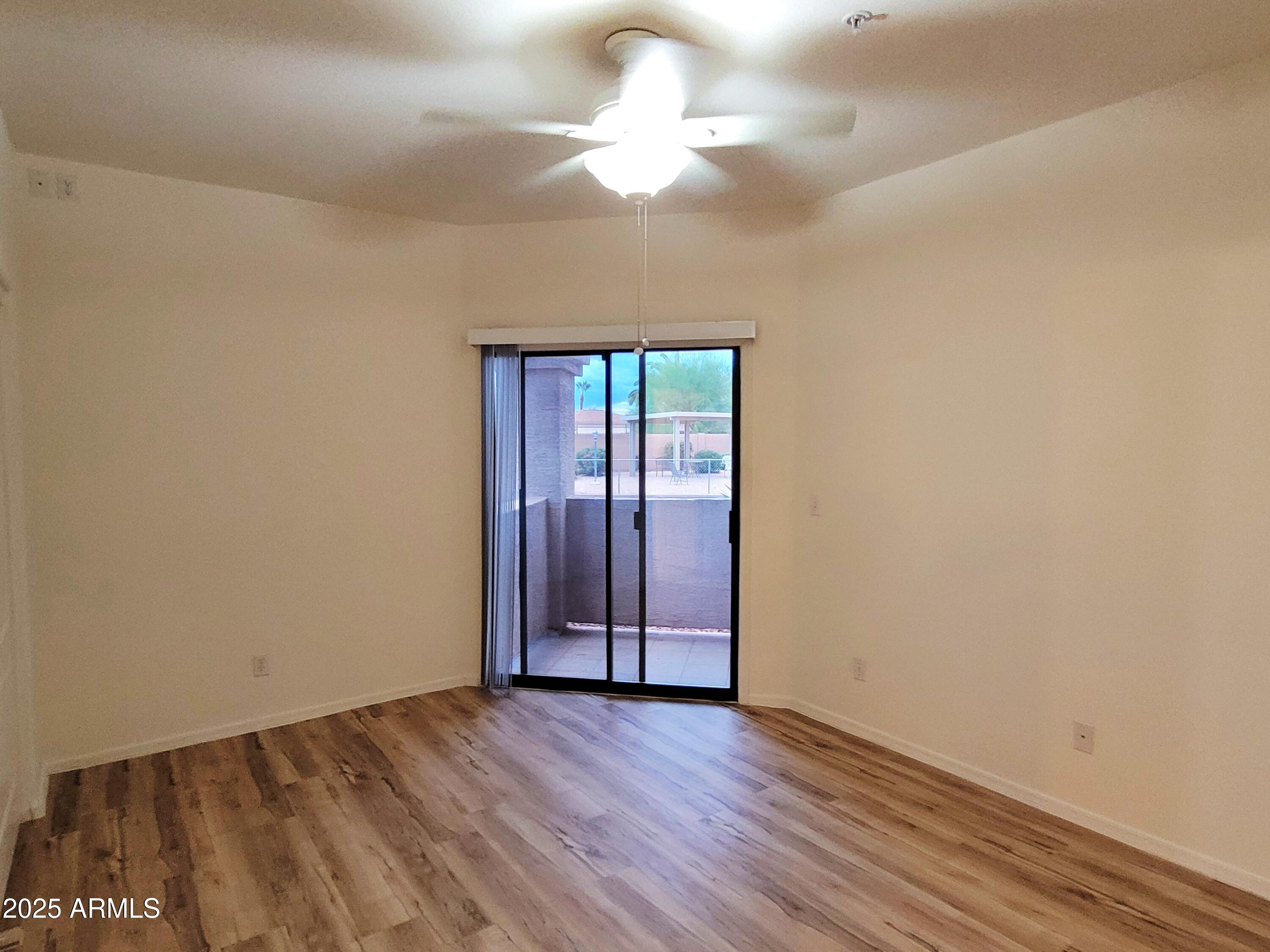 9151 West Greenway Road, Unit 152 Peoria, AZ 85381 - Photo 11 of 17 an empty room with wooden floor chandelier fan and windows