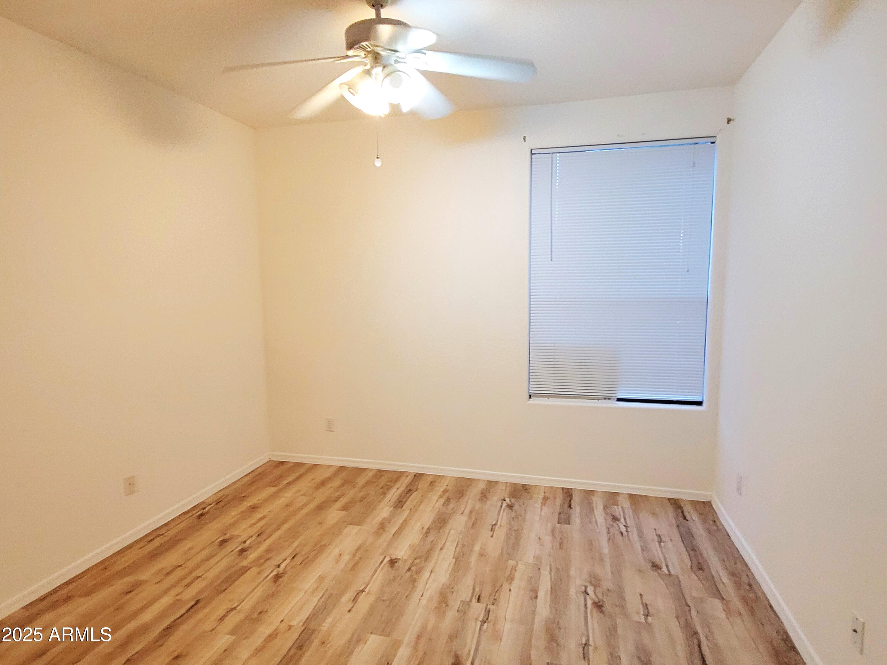9151 West Greenway Road, Unit 152 Peoria, AZ 85381 - Photo 15 of 17 an empty room with a window and wooden floor