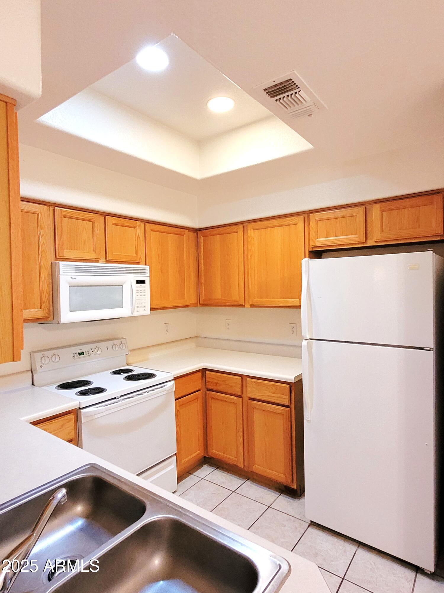 9151 West Greenway Road, Unit 152 Peoria, AZ 85381 - Photo 10 of 17 a kitchen with a refrigerator sink and cabinets