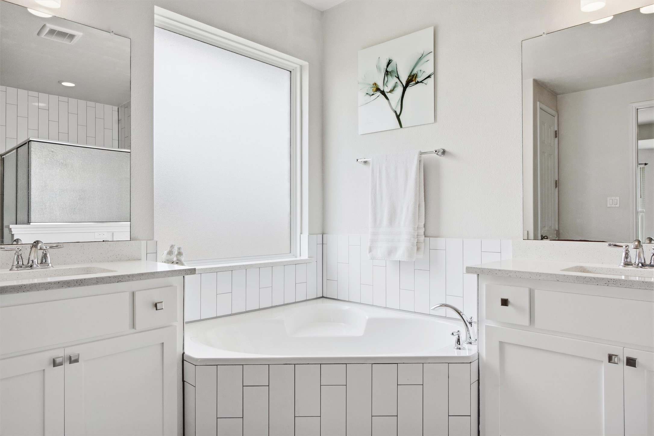 192 Raptor Beak Way Cedar Creek, TX 78612 - Photo 19 of 38 Corner soaking tub with white subway tile surround, flanked by dual vanity sinks with quartz countertops and under-sink cabinetry