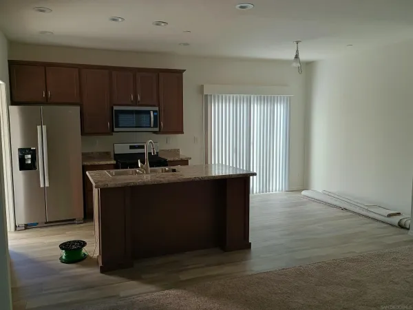 a kitchen with granite countertop wooden cabinets a refrigerator and a sink