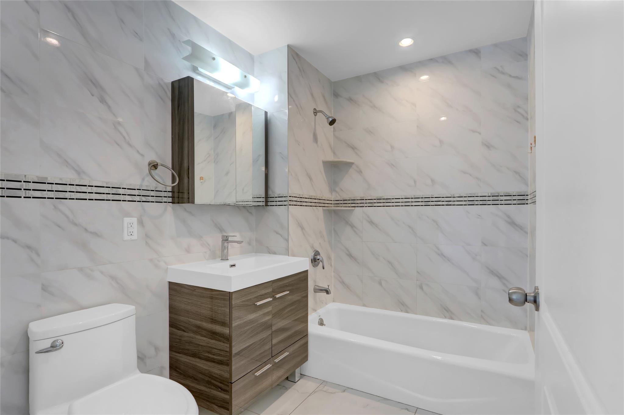 45-16 83rd Street, Unit E6J Queens, NY 11373 - Photo 12 of 19 Bathroom with vanity, toilet, shower / bath combination, marble finish floor, and tile walls