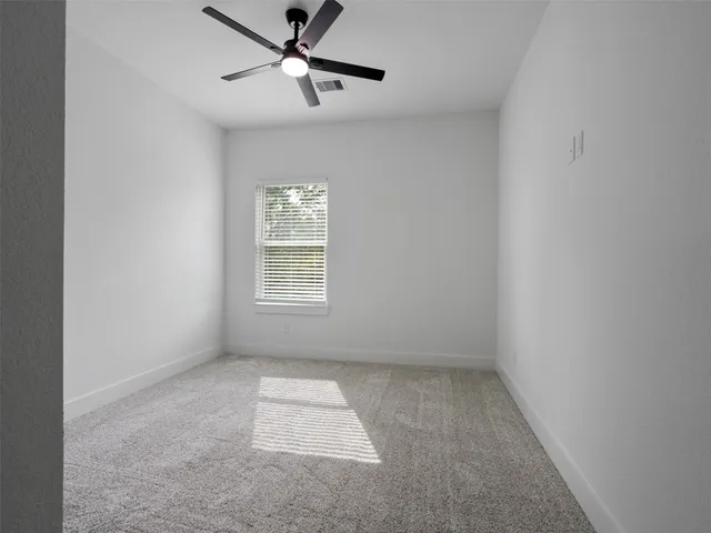 an empty room with a window and a fan