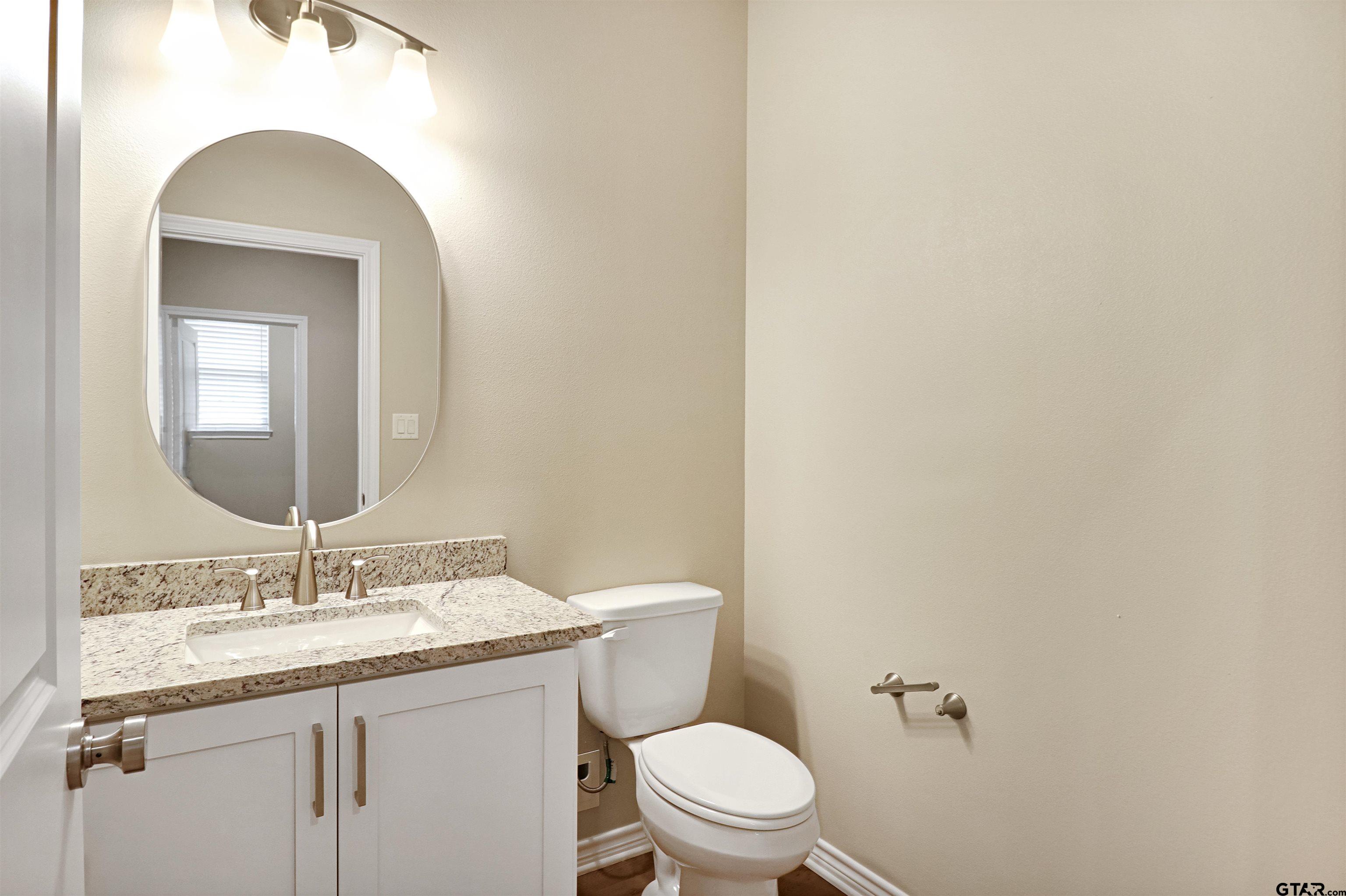 3053 Guinn Farms Road Tyler, TX 75707 - Photo 15 of 32 a bathroom with a granite countertop toilet a sink and a mirror