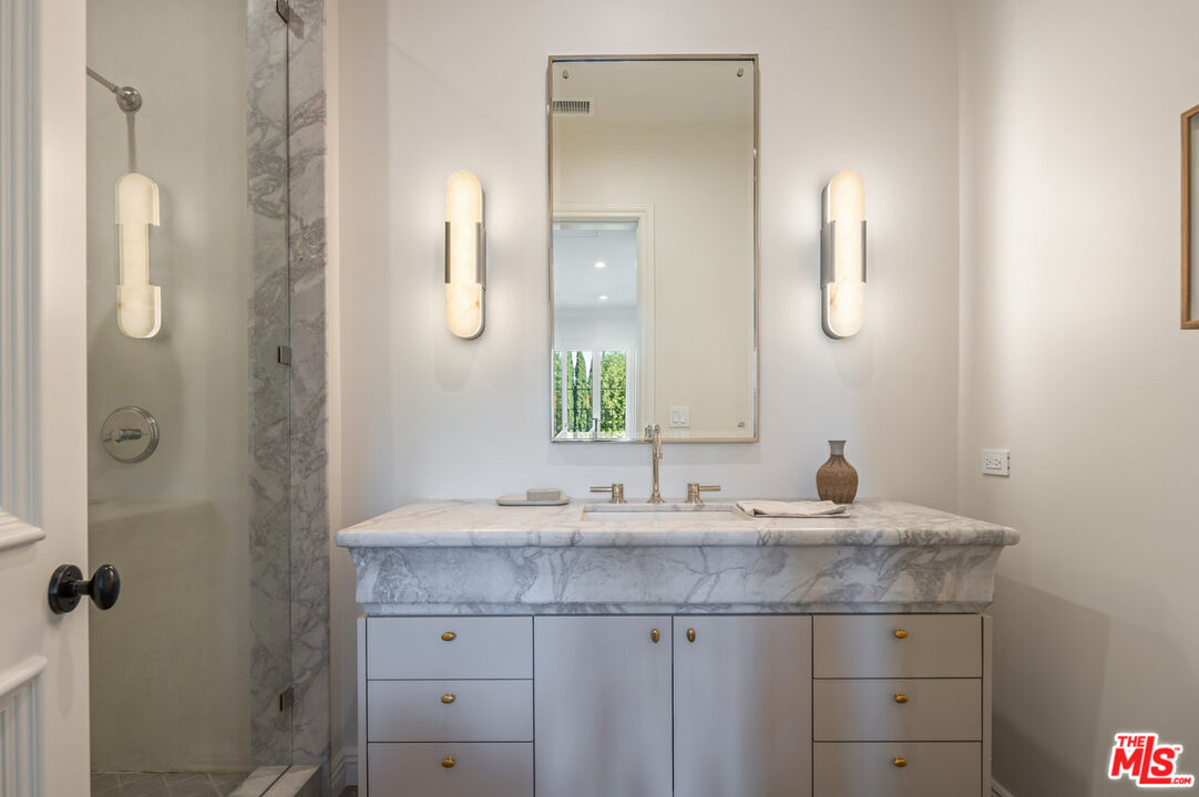 15620 Woodvale Road Encino, CA 91436 - Photo 32 of 37 a bathroom with a granite countertop sink a mirror and a shower