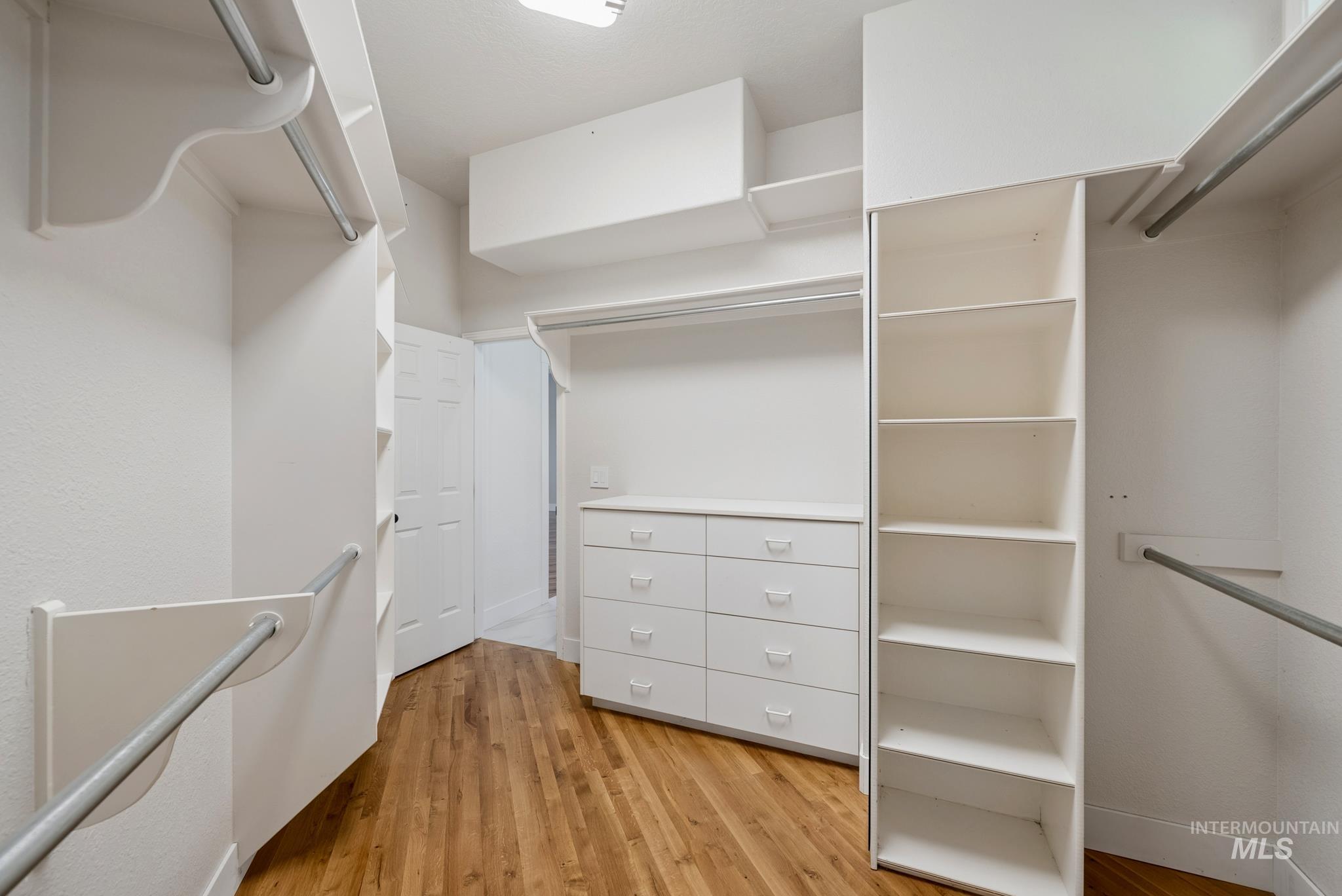 2050 Artesian Road Eagle, ID 83616 - Photo 31 of 49 Expansive walk-in closet featuring wood-finish flooring, white shelving, multiple hanging rods, built-in drawer units, and natural light from a single window