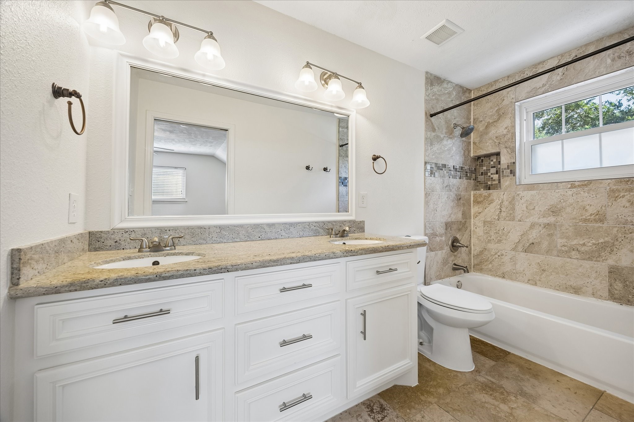 5019 Kinglet Street Houston, TX 77035 - Photo 15 of 24 Beautifully appointed primary bath boasts upgraded cabinetry, granite counters with dual undermount sinks, framed mirror, travertine flooring & upgraded hardware & plumbing fixtures.