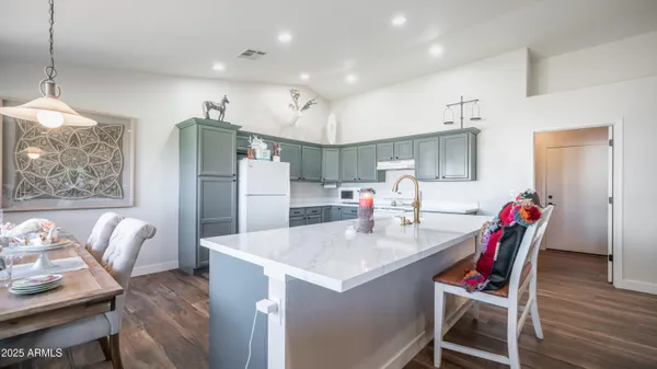 a kitchen with stainless steel appliances kitchen island granite countertop a table chairs and a refrigerator