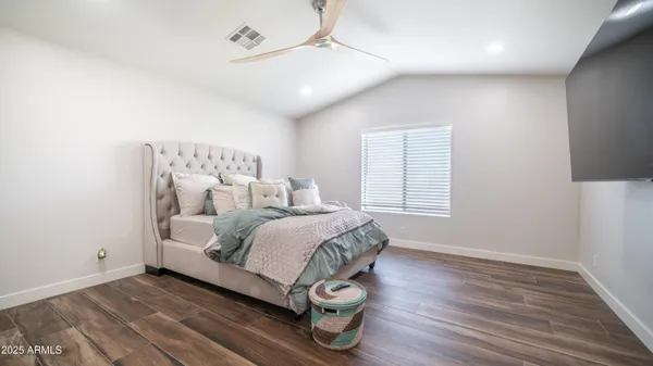 a spacious bedroom with a bed and wooden floor