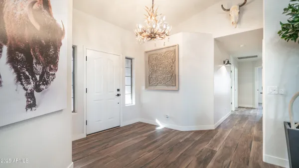 a view of a hallway with wooden floor and a chandelier