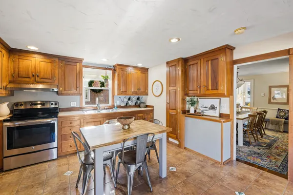 a kitchen with stainless steel appliances granite countertop a stove a refrigerator a sink a dining table and chairs with wooden floor