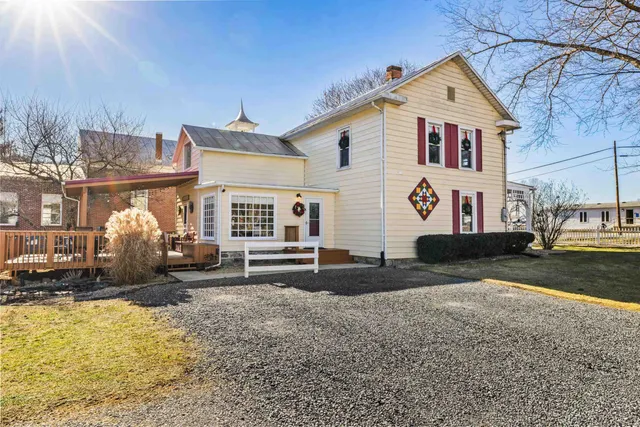a view of a white house next to a road and a yard