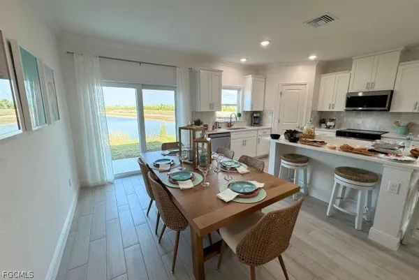 a kitchen with stainless steel appliances granite countertop a stove top oven a dining table and chairs with wooden floor