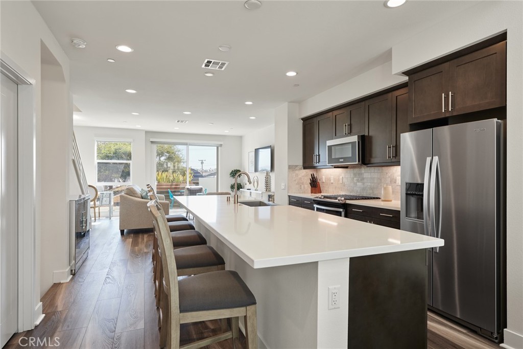 1648 Topanga Costa Mesa, CA 92627 - Photo 6 of 33 a large kitchen with kitchen island a large counter top space a sink stainless steel appliances and cabinets