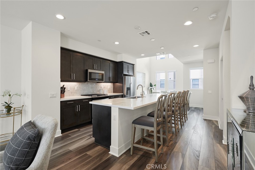 1648 Topanga Costa Mesa, CA 92627 - Photo 7 of 33 a kitchen with stainless steel appliances granite countertop a refrigerator a stove top oven a sink dishwasher and white cabinets with wooden floor