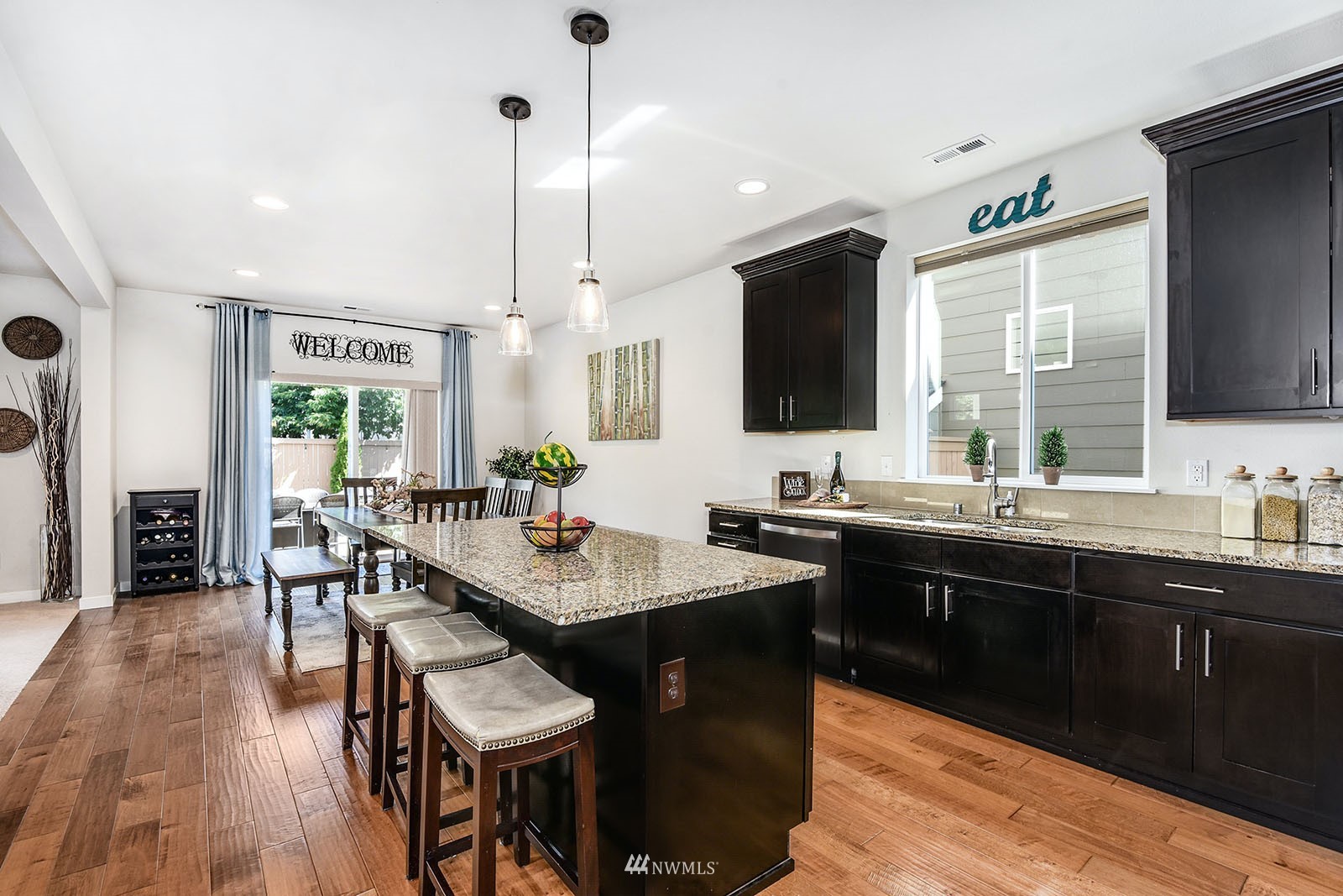 24220 Southeast 258th Way Maple Valley, WA 98038 - Photo 11 of 28 a kitchen with stainless steel appliances granite countertop wooden cabinets a dining table and chairs with wooden floor