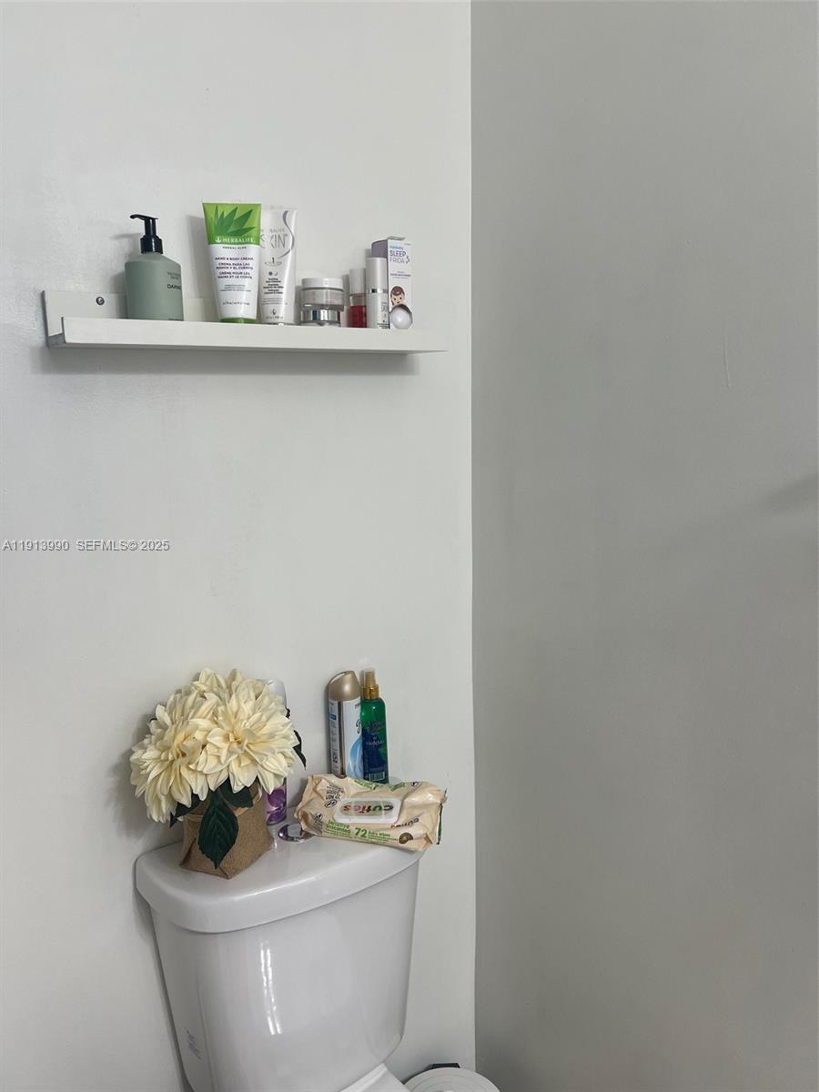 8948 Southwest 19th Street, Unit 909 Miramar, FL 33025 - Photo 23 of 31 a bathroom with a sink a toilet and a mirror