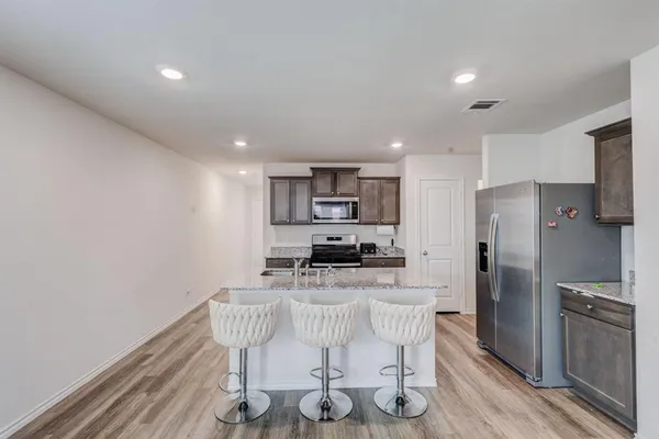 a kitchen with stainless steel appliances kitchen island granite countertop a refrigerator a stove a microwave oven with a dining table and chairs