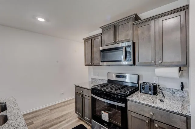 a kitchen with stainless steel appliances granite countertop a stove microwave and sink