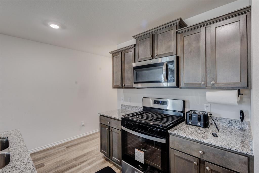 806 Ramble Road Lavon, TX 75166 - Photo 14 of 24 a kitchen with stainless steel appliances granite countertop a stove microwave and sink