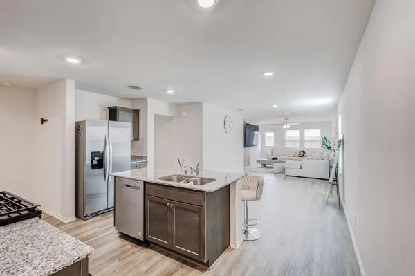a large white kitchen with a stove a sink dishwasher and a refrigerator with wooden floor