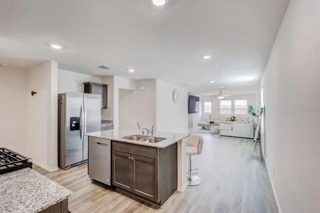 a large white kitchen with a stove a sink dishwasher and a refrigerator with wooden floor