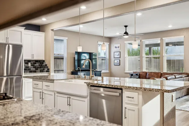 a large white kitchen with wooden floors and stainless steel appliances