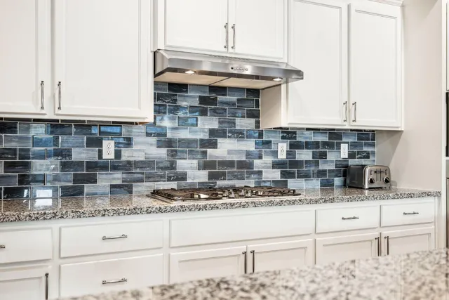 a kitchen with stainless steel appliances kitchen island granite countertop a refrigerator a stove a sink a dining table and chairs with wooden floor