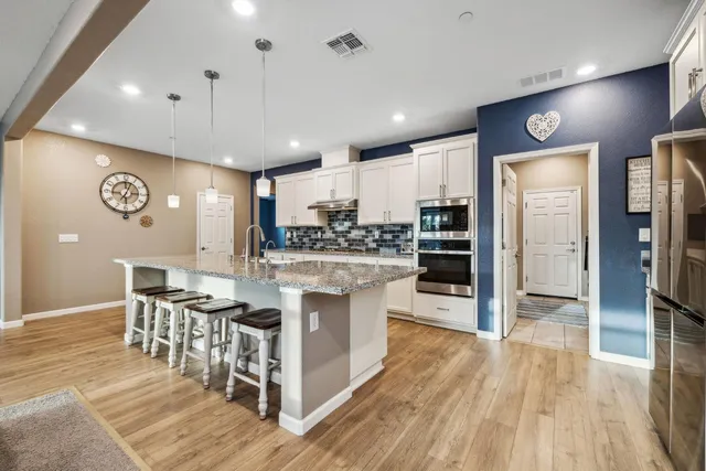 a large kitchen with kitchen island granite countertop a sink cabinets and stainless steel appliances