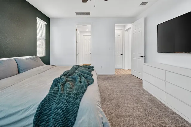 a spacious bedroom with a bed and a flat screen television