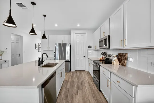 a kitchen with kitchen island granite countertop a sink a counter space stainless steel appliances and cabinets