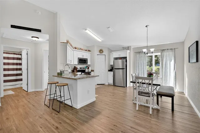 a kitchen with stainless steel appliances a dining table chairs stove and white cabinets