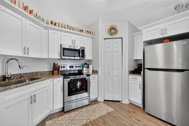 a kitchen with a refrigerator sink and white cabinets