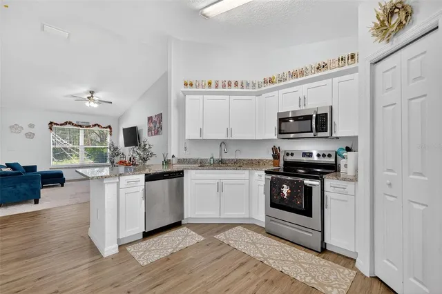 a kitchen with cabinets wooden floor and stainless steel appliances