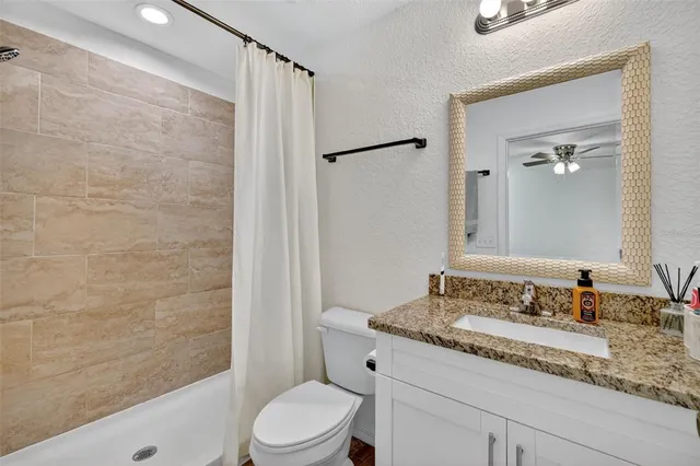 a bathroom with a granite countertop sink a toilet and shower